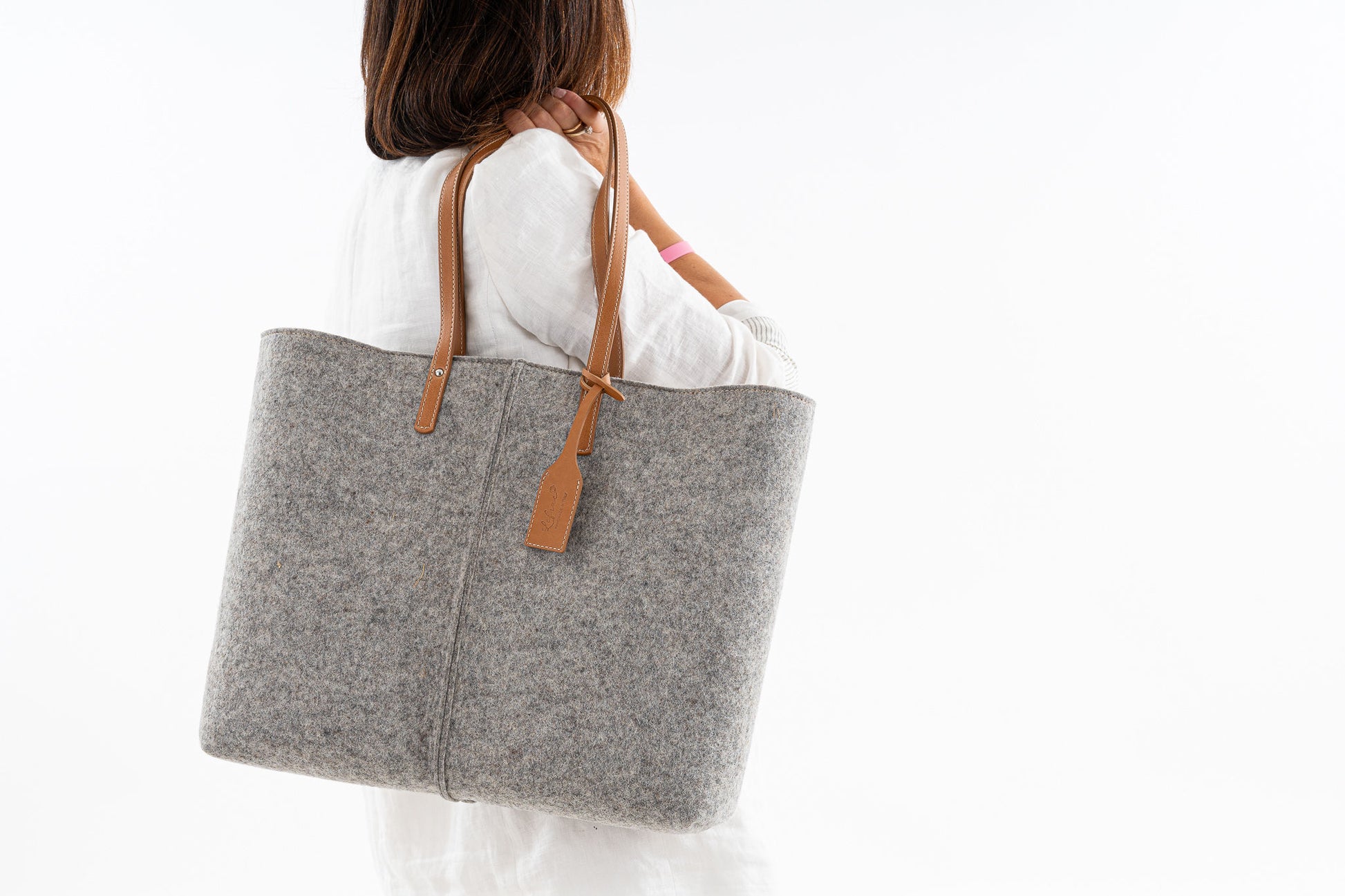 Tote Bag Large Grey made of 3mm Merino wool felt with vegan leather accents. Features include two internal pockets (one zippered, one open), a 27 cm handle drop, and a pendant with the Lefrac logo. Fits laptops up to 13”, tablets, and e-readers. Comes with a natural cotton dust bag. Handmade in Italy. - Lefrac